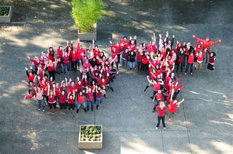 A large group of people in red t-shirts, standing in the shape of the letters O and T