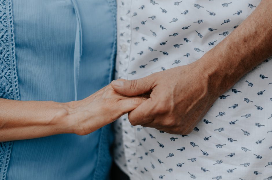 Close up of two people holding hands.