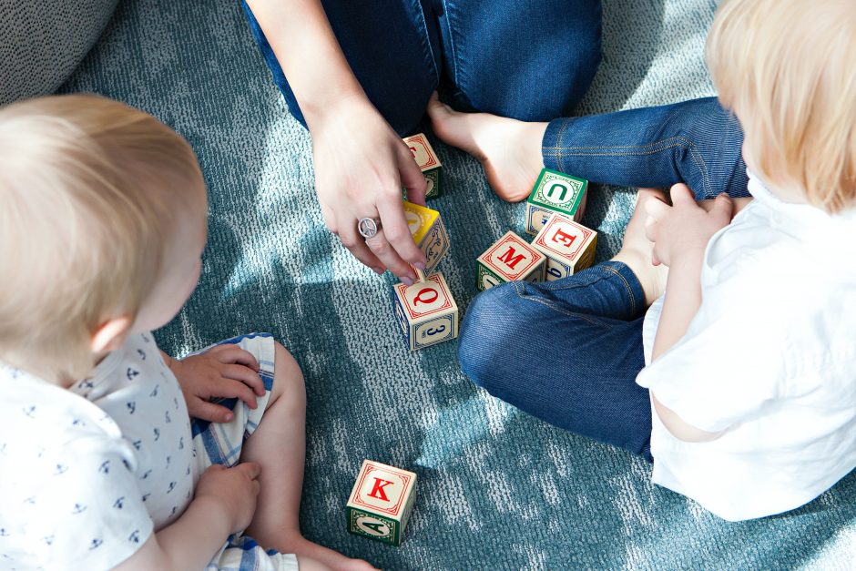 Two toddlers playing with letter bricks by Marisa Hownstine