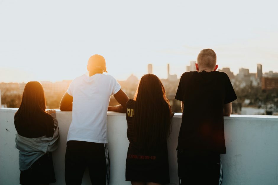 Young people on a balcony overlooking a sunset on a city skyline